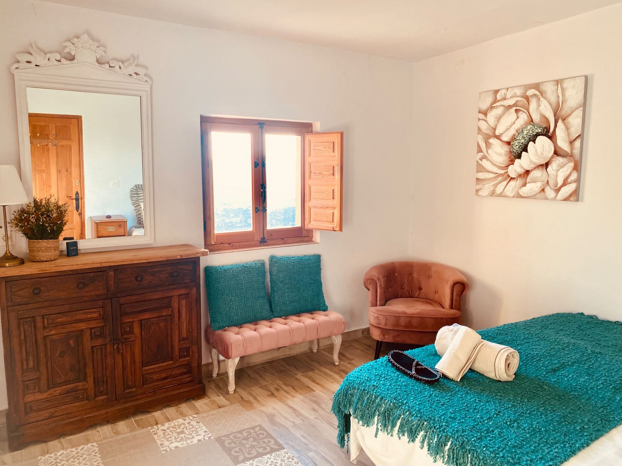 Bedroom with a tufted bench, armchair and teal throw
