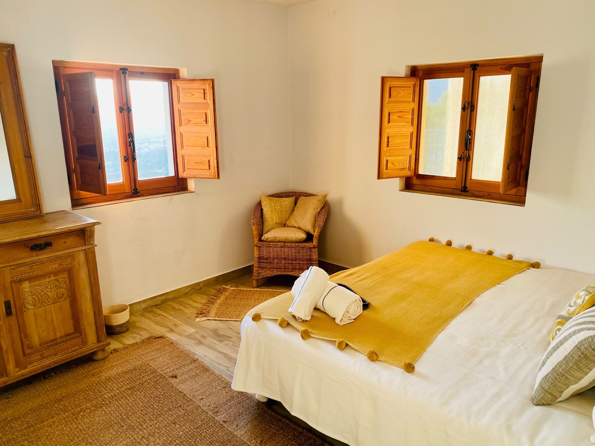 Bedroom with two shuttered windows and a wicker chair