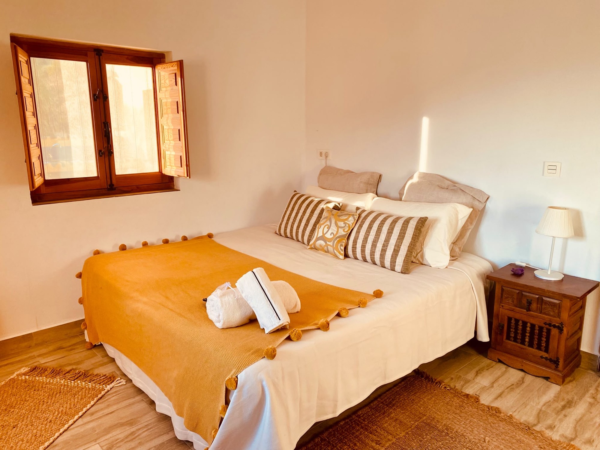 Double bedroom with a mustard throw and wooden shutters